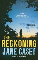 Boekcover: silhouet van een vrouw in een veld bij zonsondergang, met de titel "The Reckoning" en "Jane Casey".