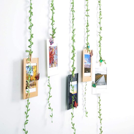 Groene klimop slingers met foto's en vlinders aan een witte muur