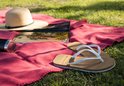 Roze plaid met een rieten hoed, tijdschrift en teenslippers.