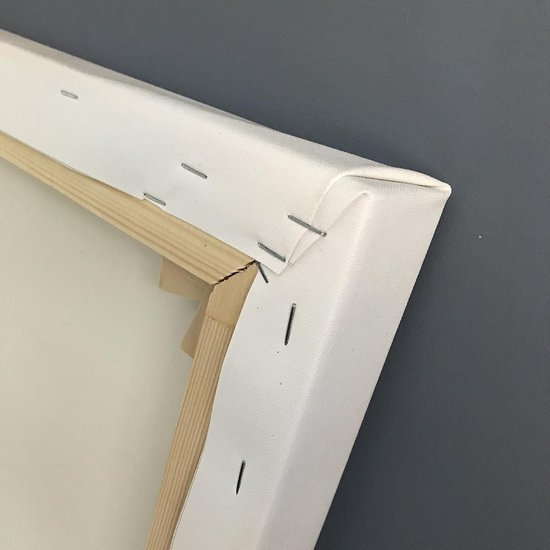 Détail d'une toile blanche avec cadre en bois et agrafes.