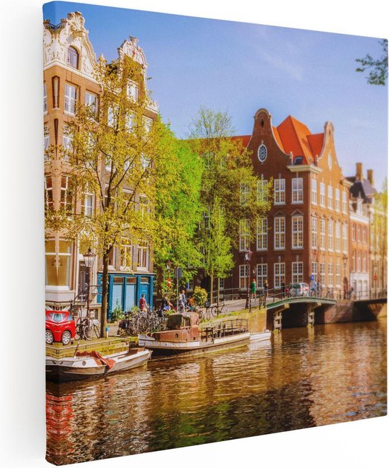 Canvas met uitzicht op Amsterdamse grachtenpanden, met een bootje op het water en groene bomen, zonnige dag.