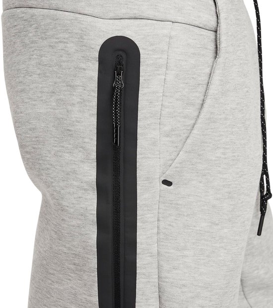 Detail van de grijze Nike joggingbroek met een zwarte ritssluiting en een zwart streepje.