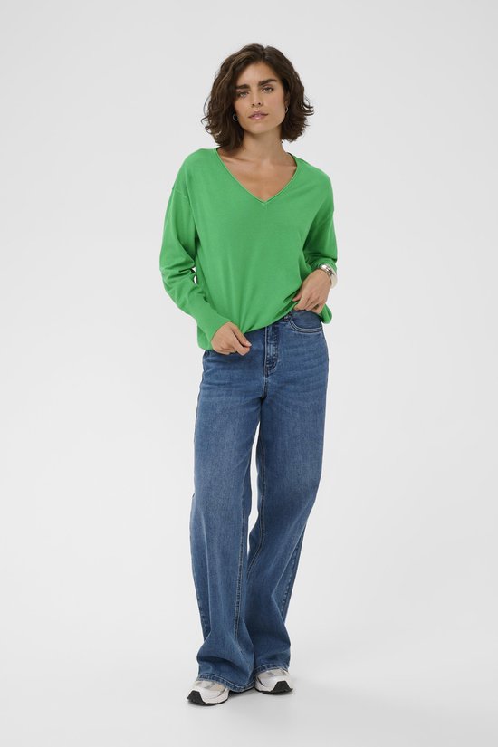 Femme portant un pull vert vif à encolure en V et un jean large.