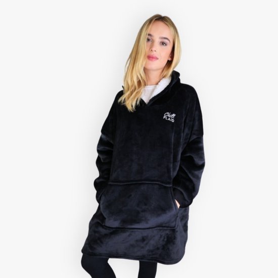 Vrouw staat met handen in de zakken van een zwarte, oversized hoodie deken. Borduursel 'Chill PLAID' op de borst.