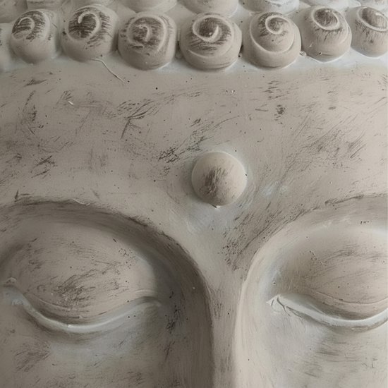 Detail van een wit Boeddahoofd: ogen, derde oog en krullend haar.