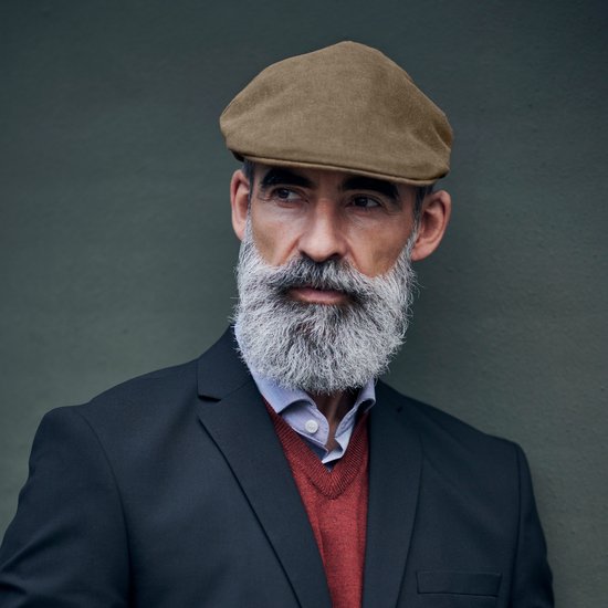 Bruine pet op een man met grijze baard en zwart jasje.