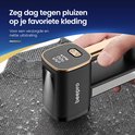 Een hand houdt een zwarte en gouden pluizenverwijderaar vast op een gebreide grijze stof. De tekst zegt: "Zeg dag tegen pluizen op je favoriete kleding"