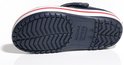 Dessous d'une Crocs Crocband bleu marine avec semelle blanche et rayures rouges. Semelle rainurée.