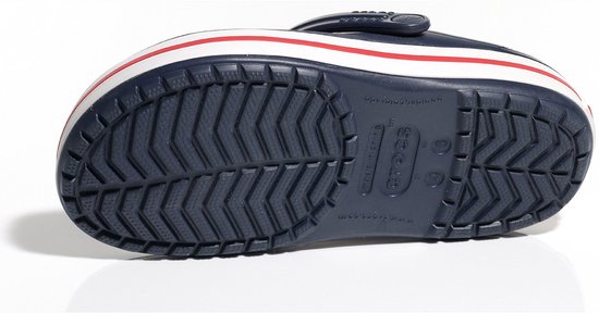 Dessous d'une Crocs Crocband bleu marine avec semelle blanche et rayures rouges. Semelle rainurée.