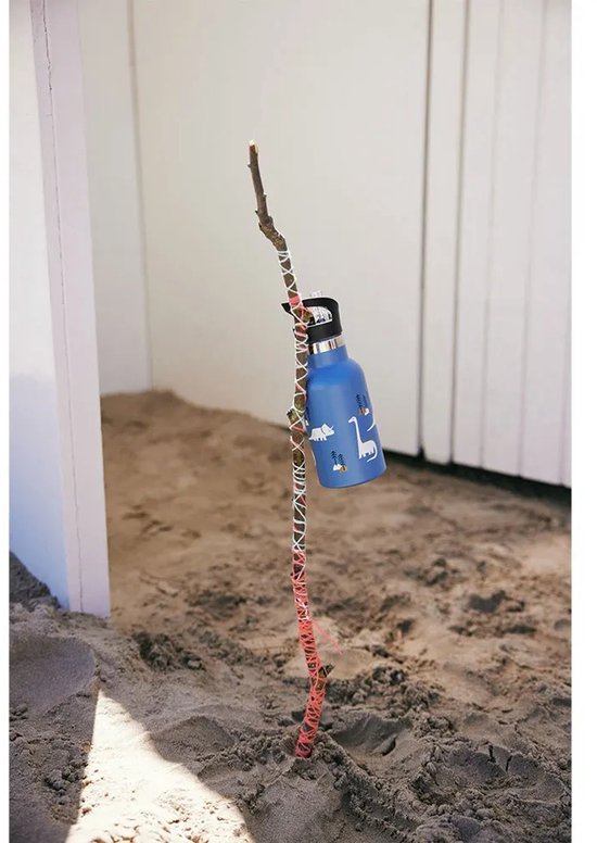 Blauwe Fresk drinkfles met dinosaurusprint hangt aan een stok op het strand.