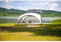 Een Coleman partytent bij een meer, met een tafel en stoelen erin.