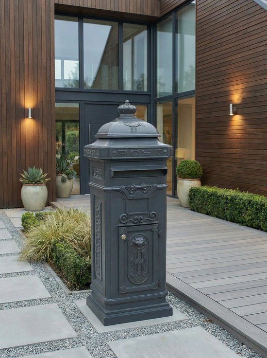 Grijze brievenbus met kroon en 'POST' opschrift, geplaatst bij een moderne entree met houten gevels en planten.