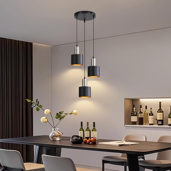 Des suspensions noires et argentées à l'intérieur doré éclairent une table à manger dans une salle à manger moderne.