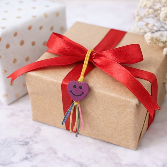 Paarse hartjes bedel met lachend gezicht aan een cadeau.