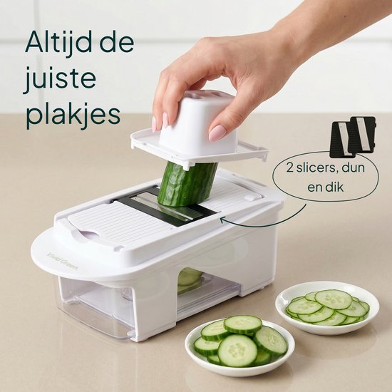 Een witte groentesnijder met mandoline-inzetstuk en komkommerschijfjes op de aanrecht. Er wordt een komkommer gesneden met twee slicers.