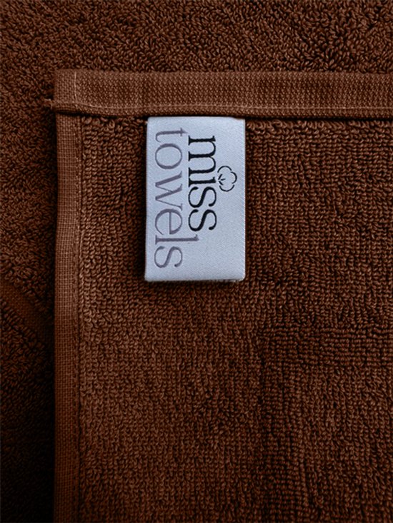 Bruine badmat met een label van Miss Towels, close-up van de textuur.