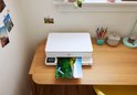 Witte HP Envy printer print een landschapsfoto op een houten bureau.
