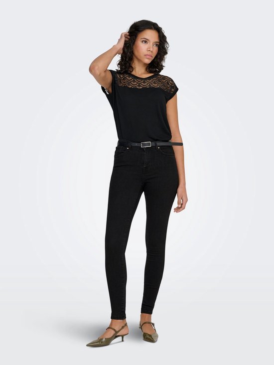 Model in zwarte skinny jeans met riem en zwart kanten topje.