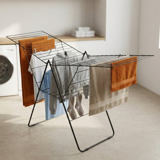 Porte-linge noir avec serviettes orange, chemise bleue et grise, chaussettes grises et serviette blanche.