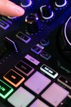 Close-up van verlichte DJ-controllerknoppen, inclusief 'loop', 'vinyl' en 'sync'.