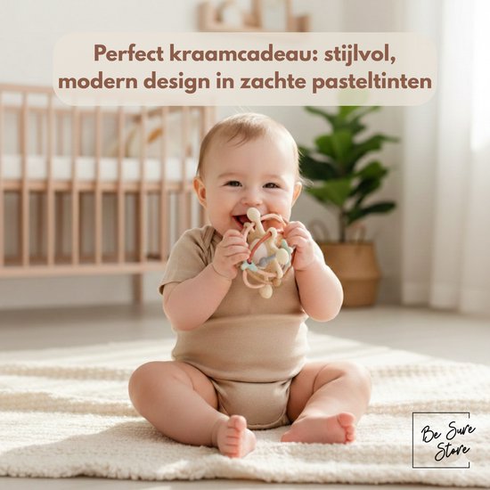 Vrolijke baby zit op de grond en houdt de pastelkleurige rammelaar en bijtring vast.