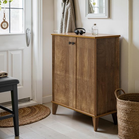 Houten schoenenkast met deuren, decoratie bovenop en een mand ernaast.