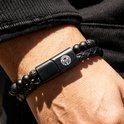 Zwarte gevlochten lederen armband met kralen van zwarte lavasteen en mat zwart, met zwarte gespsluiting.