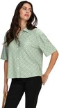 Model met lichtgroene blouse met broderie anglaise en zwarte broek.