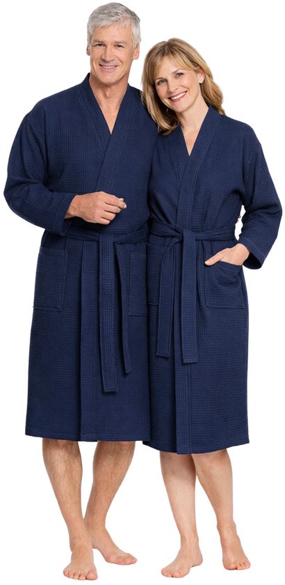 Een oudere man en een jongere vrouw staan naast elkaar in marineblauwe wafelkatoenen badjassen met riemen.