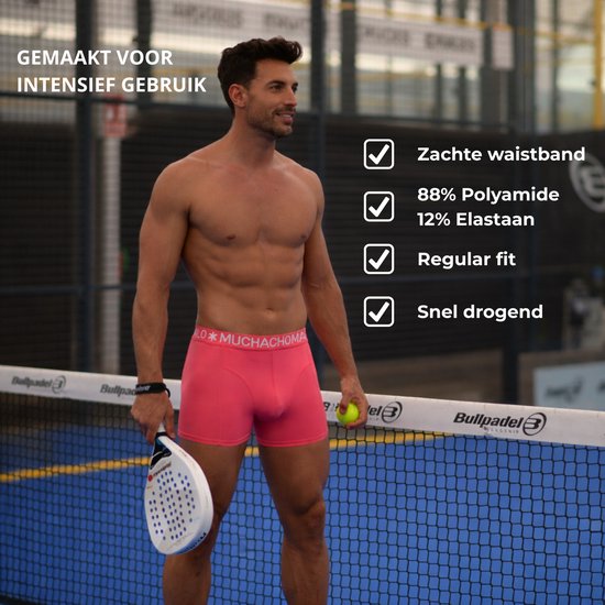 Man in roze Muchachomalo boxershorts op een padelbaan. Links checklist met 'Zachte waistband', '88% Polyamide 12% Elastaan', 'Regular fit', 'Snel drogend'.