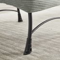 Zwarte metalen poten van een lichtgroene corduroy stoel, details.