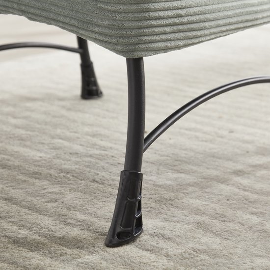 Zwarte metalen poten van een lichtgroene corduroy stoel, details.