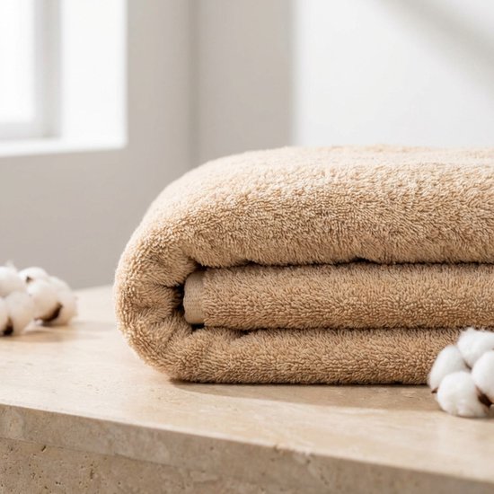 Serviette beige pliée avec des fleurs de coton sur une surface en pierre.