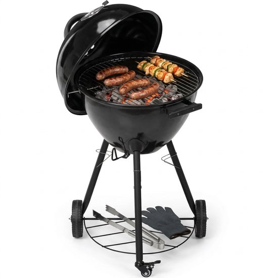 Zwarte kogelbarbecue met open deksel, grillt worstjes en saté, met kolen, tangen en handschoen.