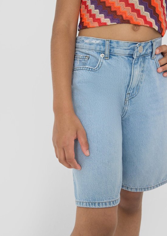 Gedetailleerde close-up van een lichtblauwe denim bermudashort gedragen door een meisje.
