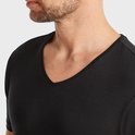 Close-up van een man met zwart t-shirt, V-hals zichtbaar.