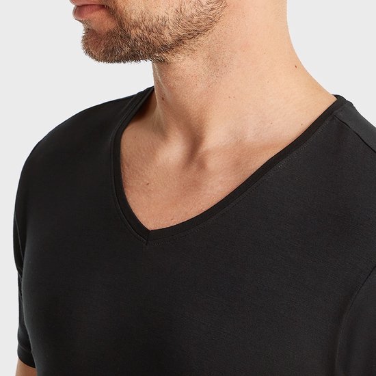 Close-up van een man met zwart t-shirt, V-hals zichtbaar.