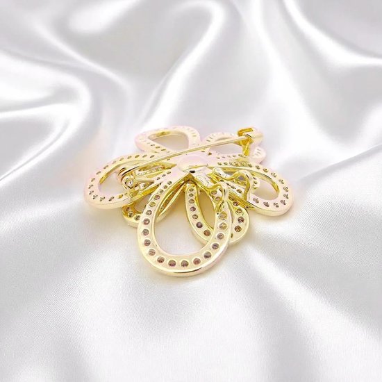 Gouden cosmosbloem broche met zirkonia, achterkant zichtbaar op satijn.