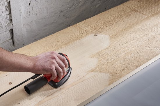 Hand schuurt onbehandeld hout met een schuurmachine, waardoor de houtnerf zichtbaar wordt.