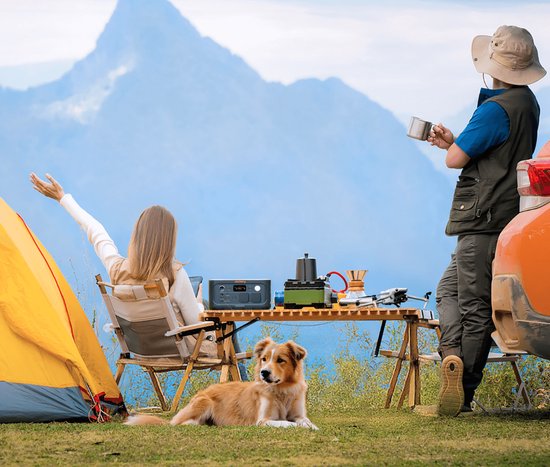 Jackery Explorer 500 powerstation op een tafel naast een tent en bergen.