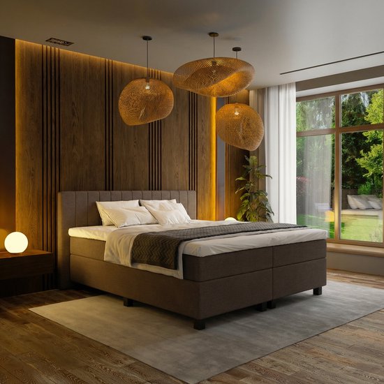 Un lit boxspring Mörgenn de 120x200 cm en tissu marron, avec une tête de lit capitonnée et une couverture et des oreillers blancs.