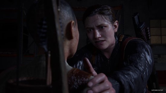 Ellie grijpt een persoon bij de kin in een donkere omgeving.