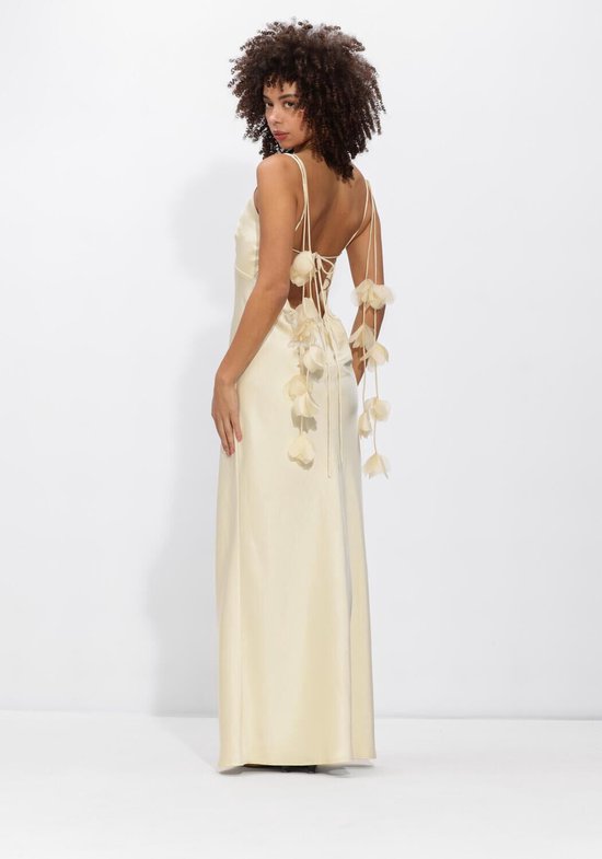 Mannequin dans une robe maxi en satin crème, avec des détails floraux dans le dos attachés par un ruban.