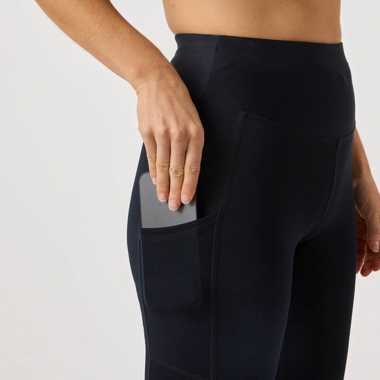 Dichtbij profiel van zwarte sportlegging, telefoon wordt in het zijvak geschoven.