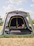 Een gezin geniet van een tent met Coleman BlackOut Bedroom technologie. "Coleman Blackout Bedroom Technology" en "Keeps up to 99% of daylight out of your sleeping area." op de afbeelding.