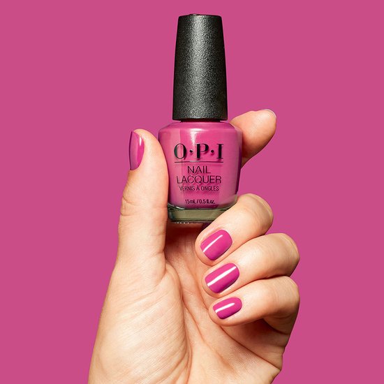Een hand met een roze nagellakflesje O.P.I. Nail Lacquer Strawberry Cosmo. Nagels zijn gelakt in dezelfde kleur.