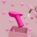 Roze Lovense Ambi Mini vibrator zwevend uit een open roze geschenkdoos, omringd door roze hartjes.
