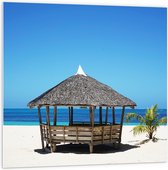 WallClassics - PVC Schuimplaat- Rieten Hutje op Wit Zand bij Blauwe Zee - 100x100 cm Foto op PVC Schuimplaat