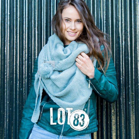 Model draagt een mintgroene gebreide LOT83 sjaal met pompon en een groen leren jasje.