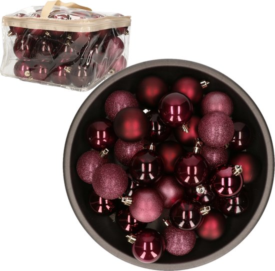 Boules de Noël rouge foncé dans un bol rond et un sac de rangement transparent. Les boules ont des finitions brillantes et mates.